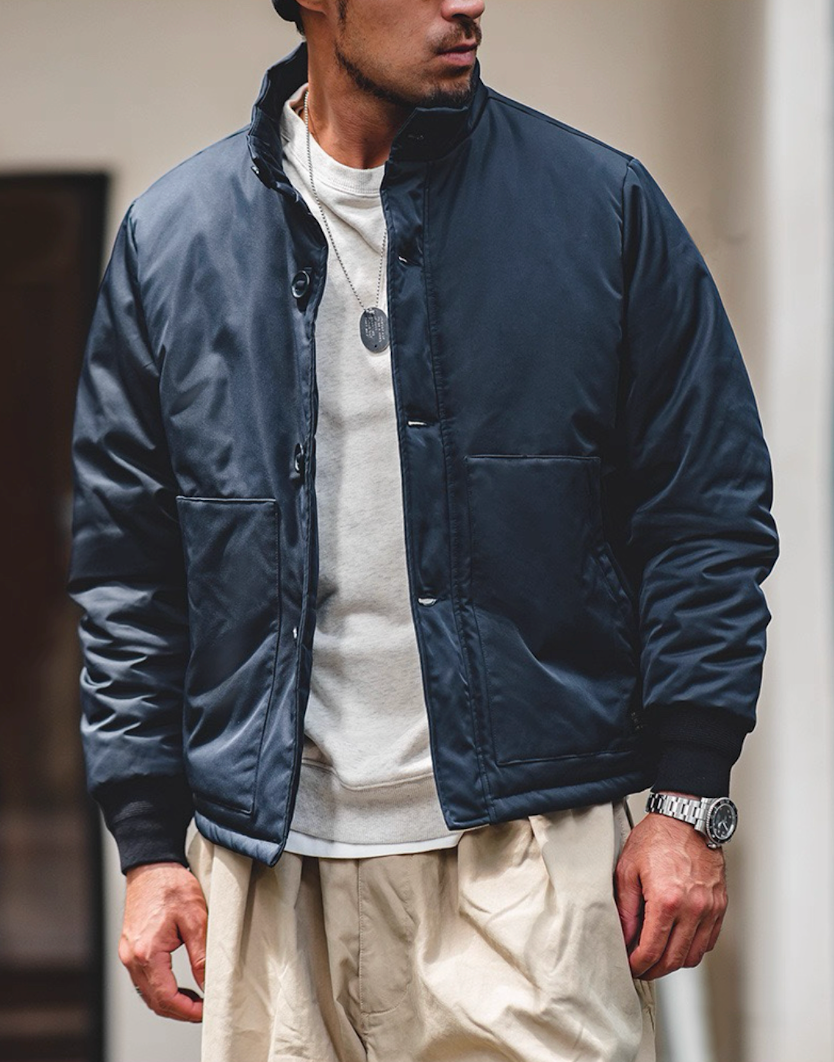 Navy military-style padded jacket on model outdoors, streetwear styling.