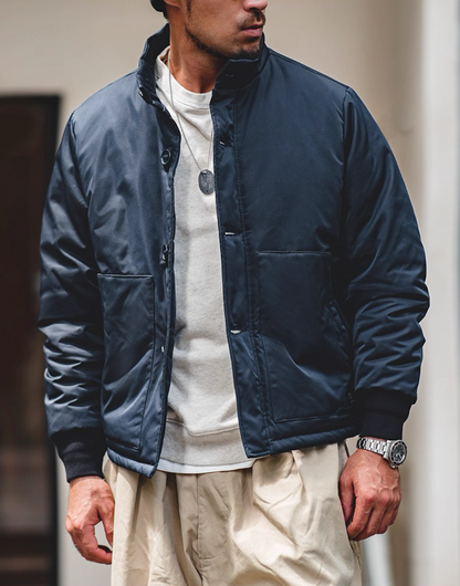 Navy military-style padded jacket on model outdoors, streetwear styling.