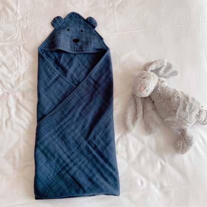 Bear Navy Blue hooded cotton muslin baby swaddle wrap fully wrapped on bed with plush toy showing cozy design