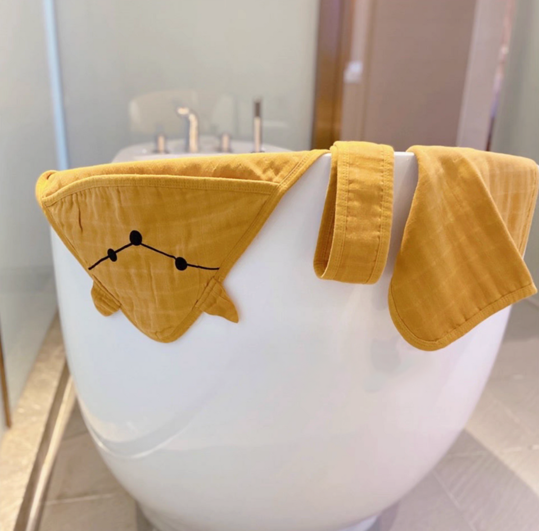 Fox Orange baby swaddle wrap with hood and matching belt draped over bathtub showing breathable cotton muslin texture