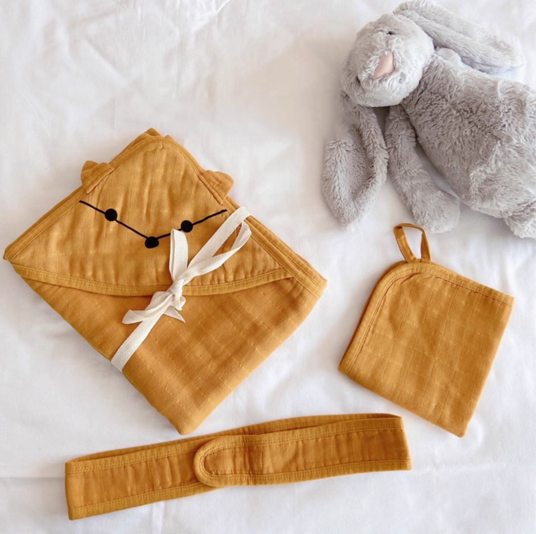 Fox Orange hooded cotton muslin baby swaddle wrap set with matching belt and cloth laid flat on bed with plush toy