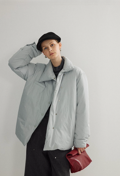 Ice Blue down jacket worn partly open, showing the asymmetric snap front and chest welt pocket