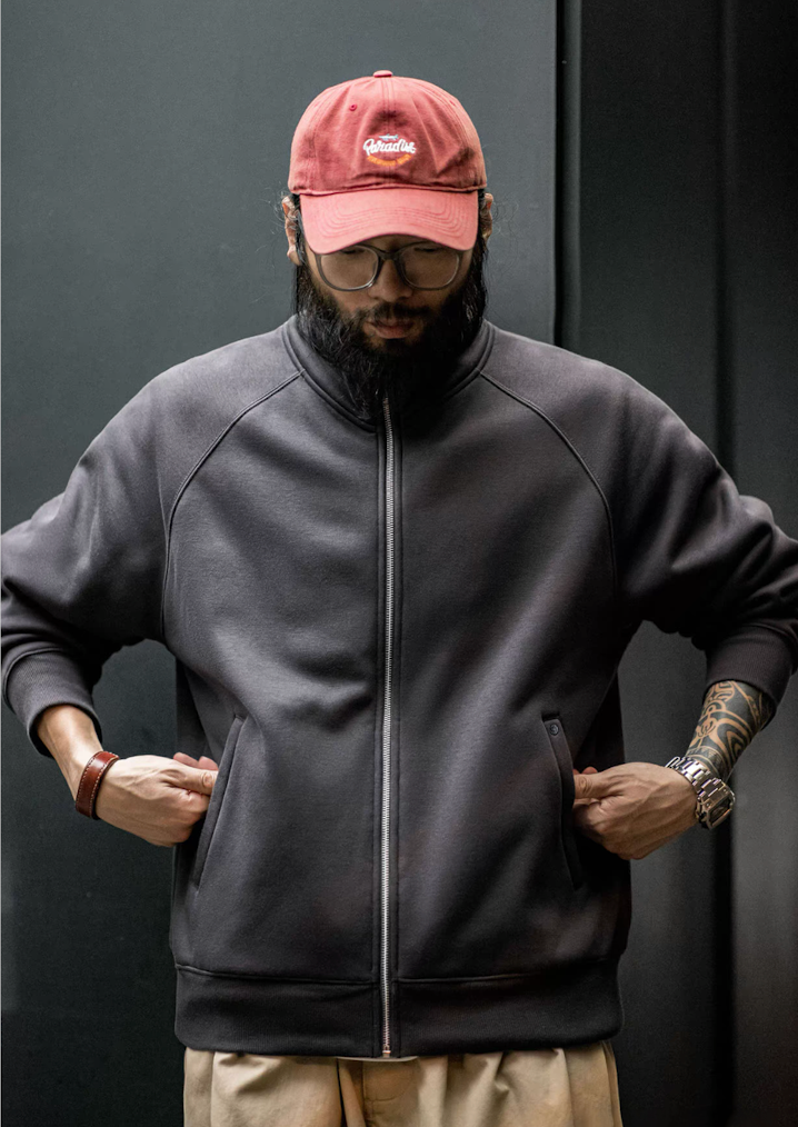 Charcoal fleece zip jacket on model with hands in pockets, raglan sleeves