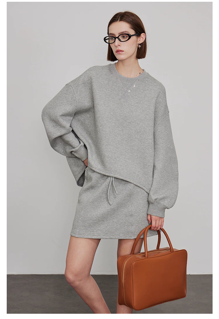 Grey oversized sweatshirt and skirt outfit styled with brown leather bag