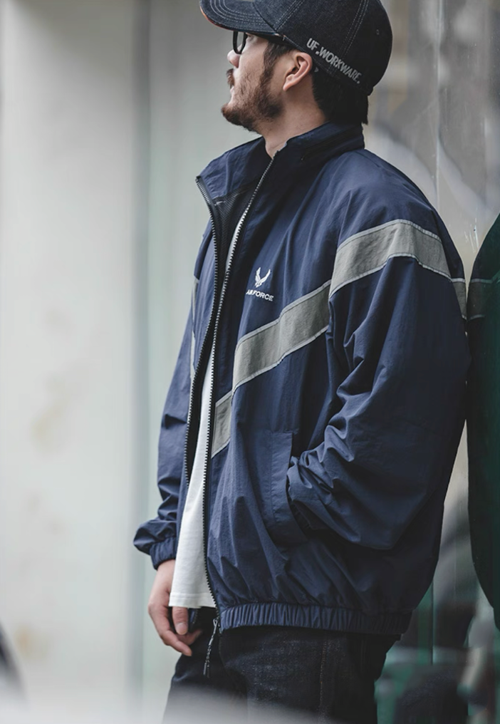 Side profile of model wearing navy blue AIR FORCE training jacket.