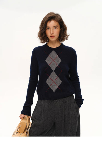 Front view of model wearing navy 100% wool argyle crewneck sweater with gray wide-leg trousers.