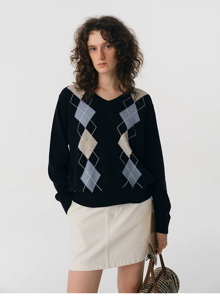 Front view of navy V-neck wool sweater with light blue and beige argyle pattern.