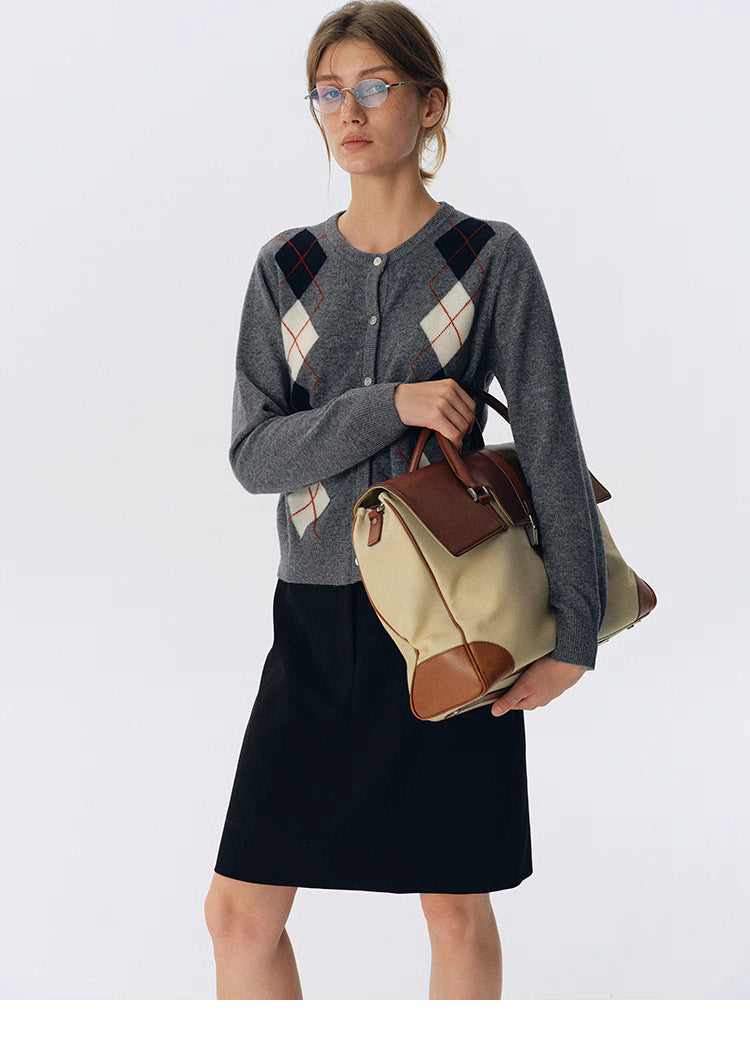 Full-body view of charcoal gray argyle wool button-up cardigan styled with a black skirt and tan travel bag.