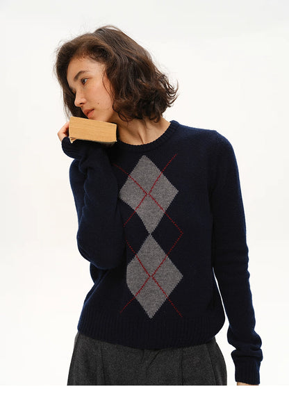 Side pose of model in navy argyle wool crewneck sweater resting a book against her face.