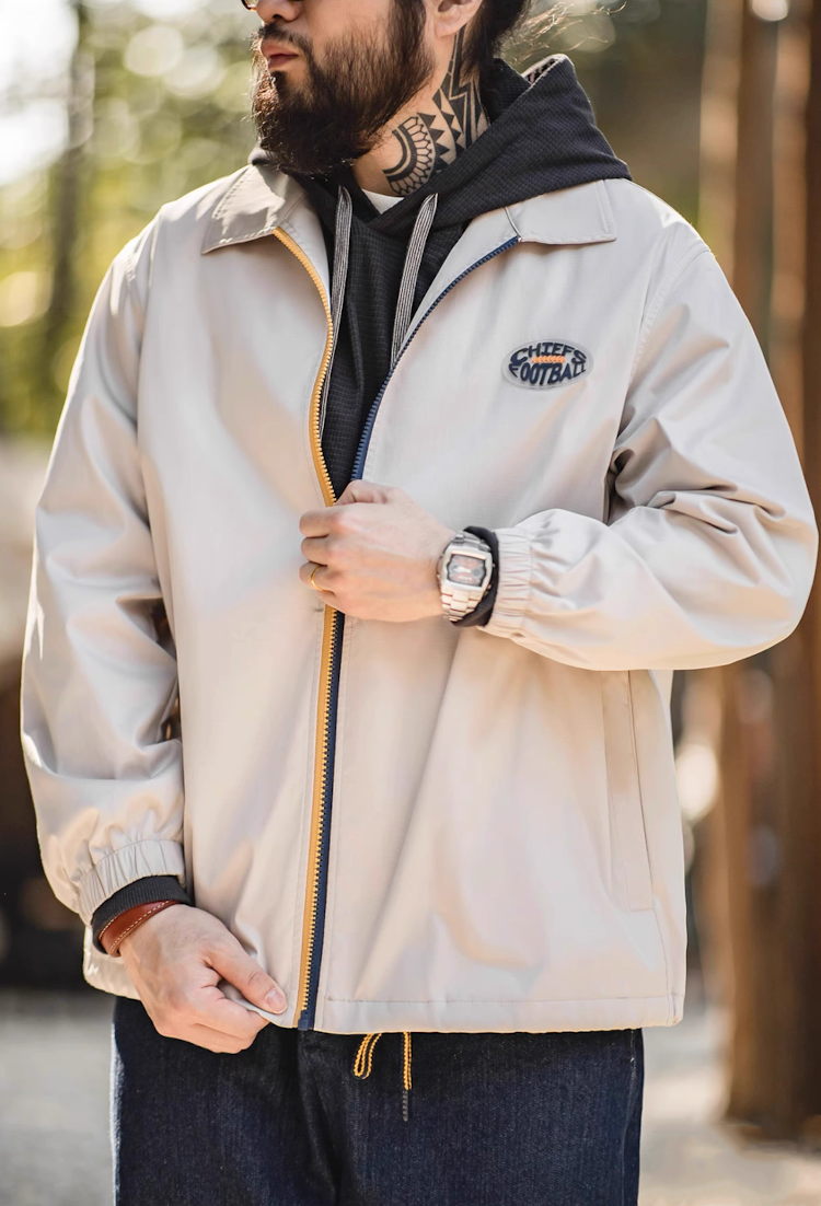 Man wearing off-white coach jacket layered with hoodie, outdoor street style.