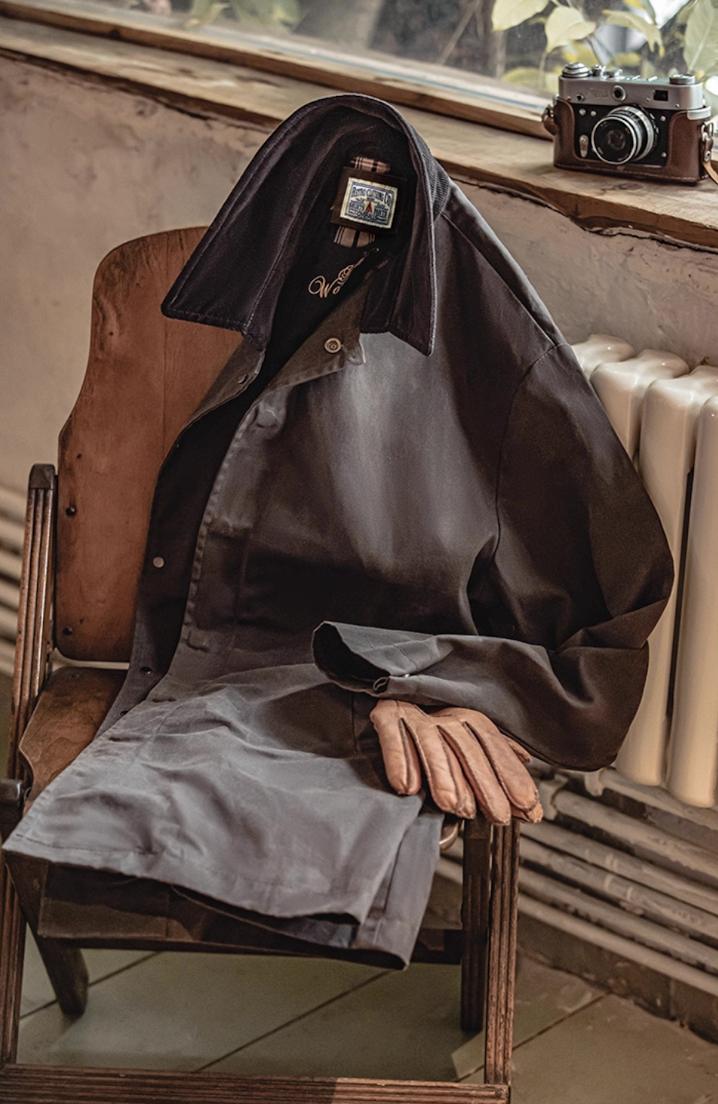 Waxed cotton heritage coat draped on chair with gloves