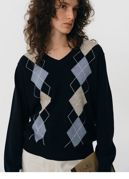 Close-up of navy V-neck wool sweater showing light blue and beige woven argyle design.