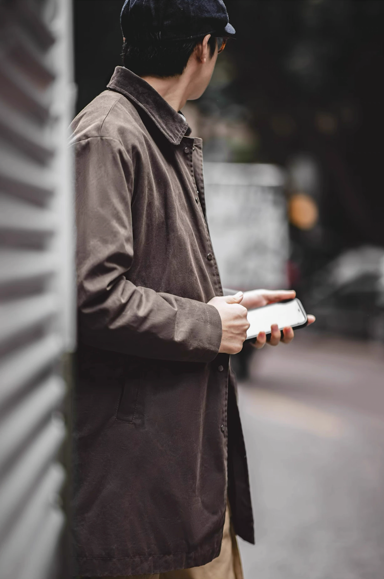 Men’s waxed cotton coat worn outdoors in urban setting