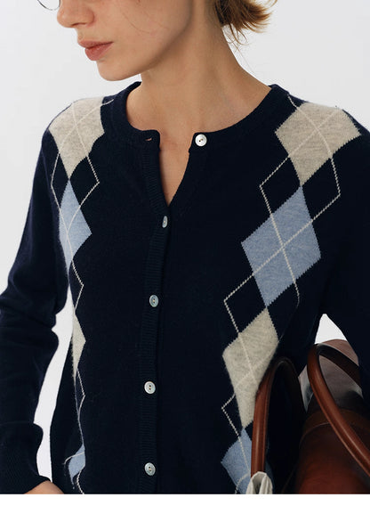 Close-up of navy wool argyle cardigan showing light blue and beige diamond knit pattern and button placket.