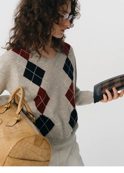 Close-up of oat gray V-neck wool sweater showing burgundy and navy argyle pattern.