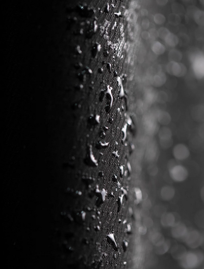 Close-up of water-repellent coated black fabric with droplets.
