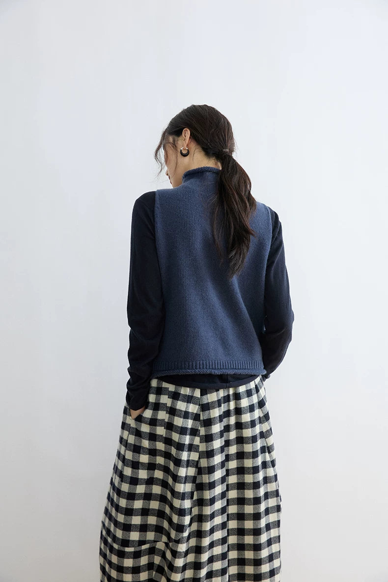 Back view of Ink Blue mock-neck sweater vest layered over a navy long-sleeve top