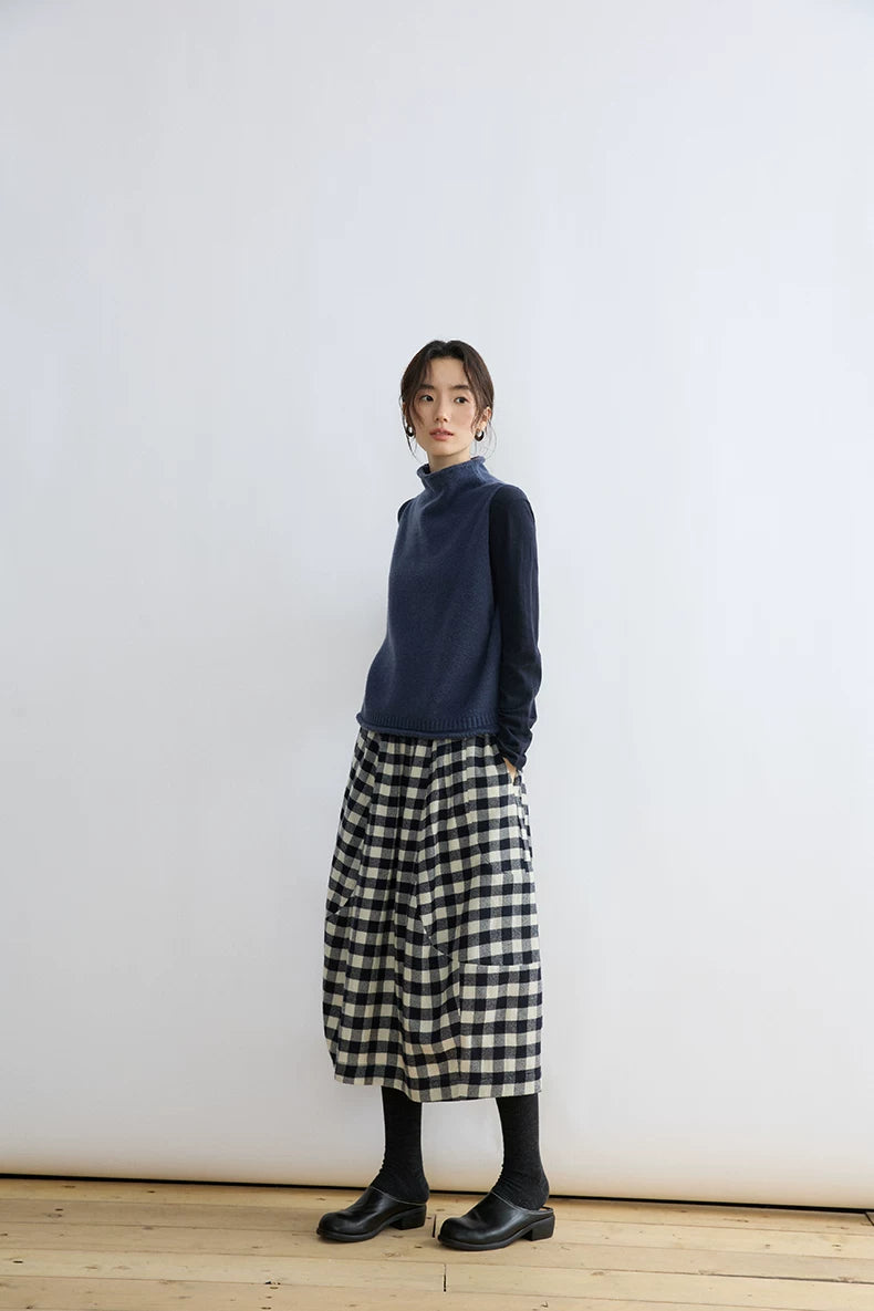 Full-length front view of Ink Blue cropped sweater vest styled with a gingham midi skirt and black shoes