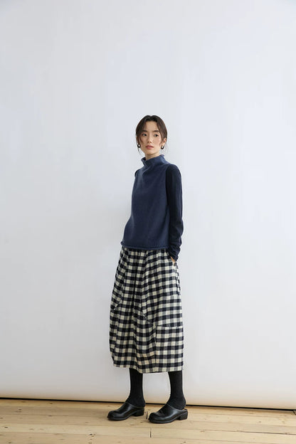Full-length front view of Ink Blue cropped sweater vest styled with a gingham midi skirt and black shoes