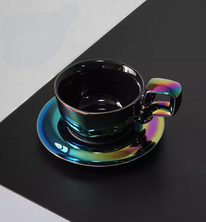 Aurora Black iridescent balloon-handle ceramic coffee mug with saucer, angled front view showing dark glossy color-shifting finish