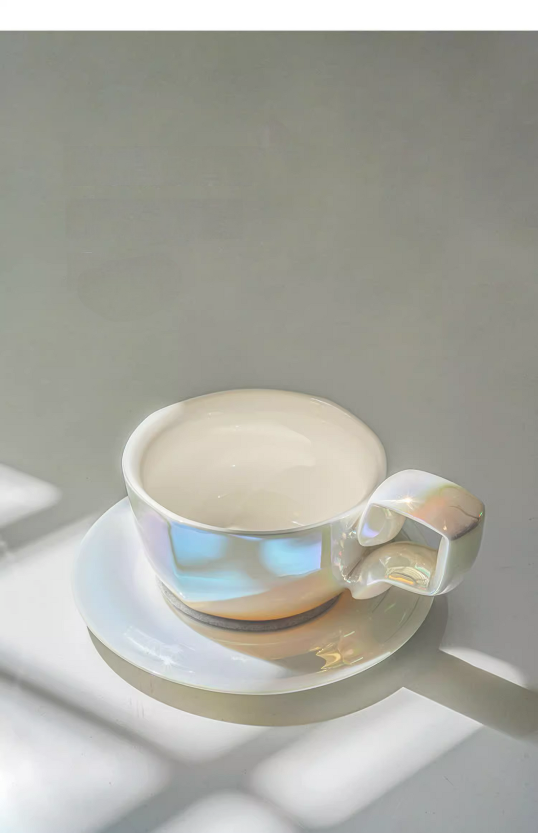 Pearlized Mother of Pearl White iridescent balloon-handle ceramic coffee mug with saucer, front view under natural light