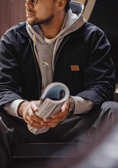 Ironclad Canvas Work Jacket black casual lifestyle sitting pose styled with hoodie showing relaxed fit and everyday wear versatility
