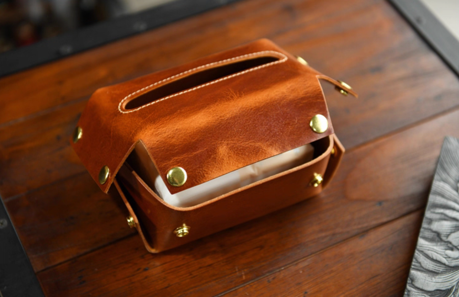 Open view of caramel leather tissue box showing tissue inside and brass snap details.