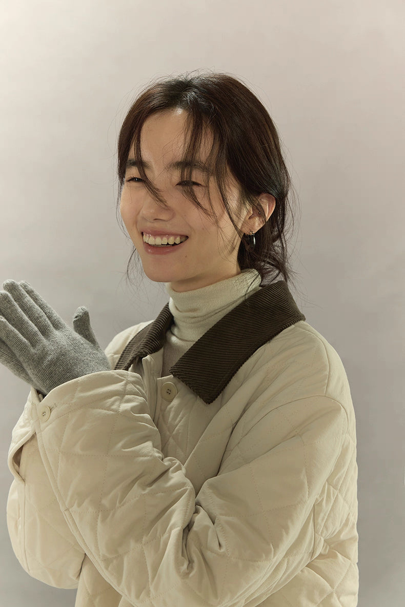 close-up of model smiling in quilted coat with charcoal corduroy collar