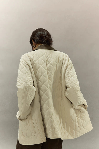 back view of mid-length cream quilted coat with diamond stitching