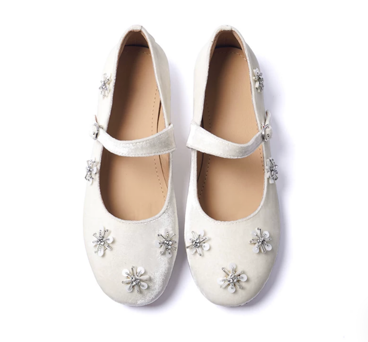 Top-down view of Ivory velvet Mary Janes with rhinestone-centered starburst motifs