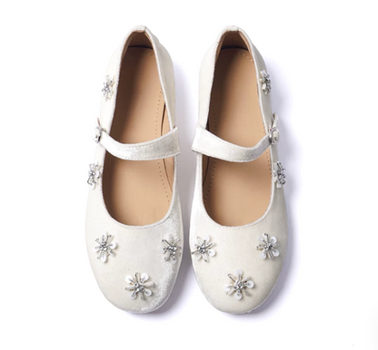Top-down view of Ivory velvet Mary Janes with rhinestone-centered starburst motifs