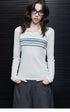Woman wearing Ivory Stripe fitted polo sweater with blue, navy and green chest stripes and grey trousers