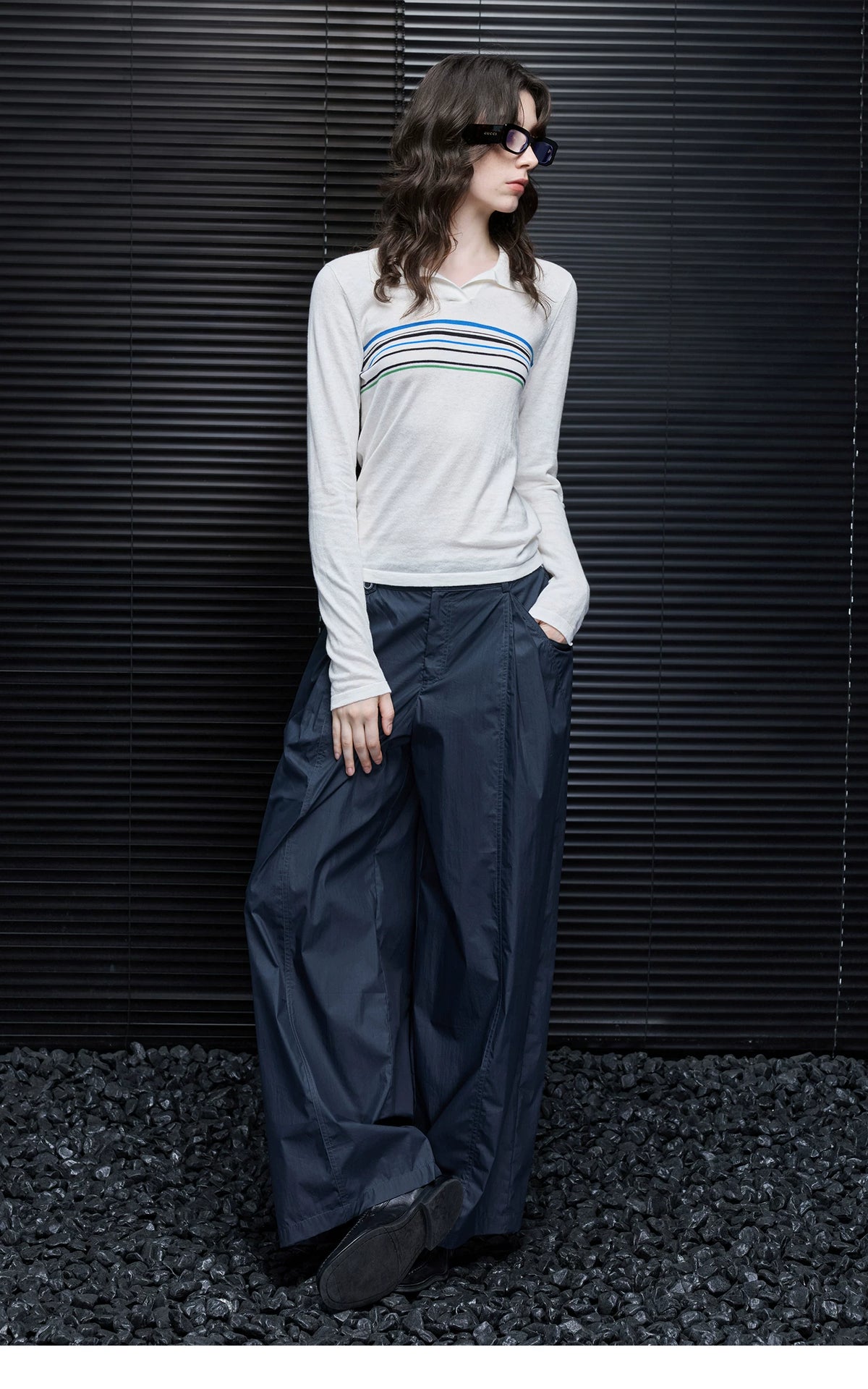 Model leaning against a wall in Ivory Stripe cotton-cashmere polo sweater and navy wide-leg pants