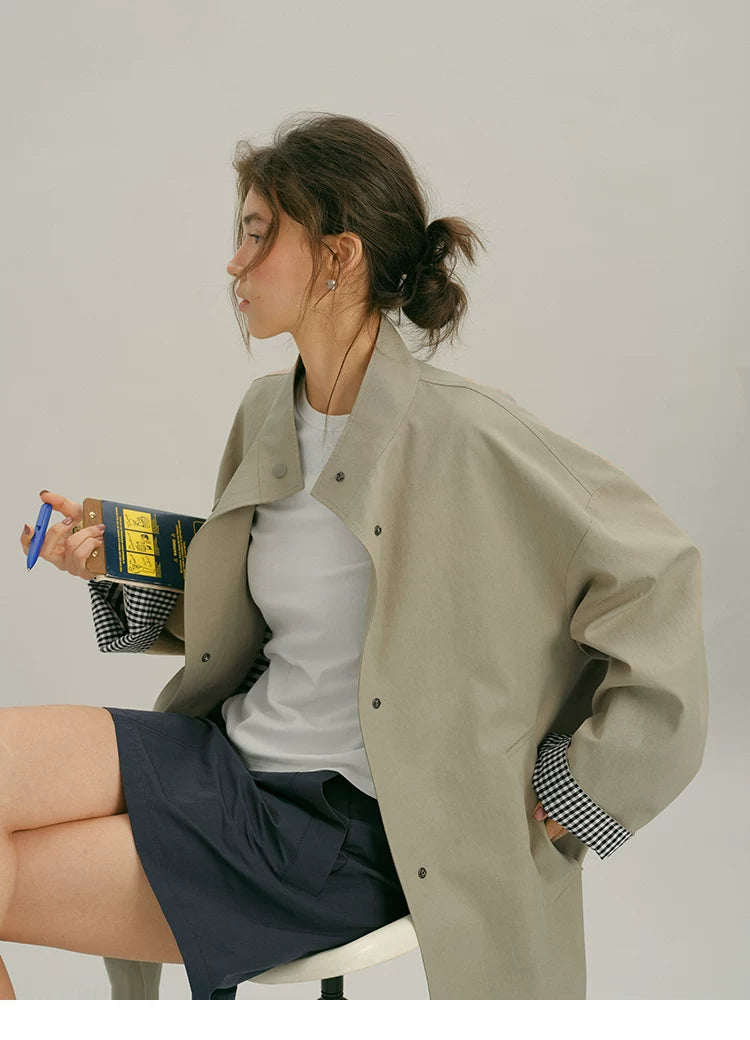 Seated profile of a Khaki mac coat showing the stand collar and gingham cuff lining