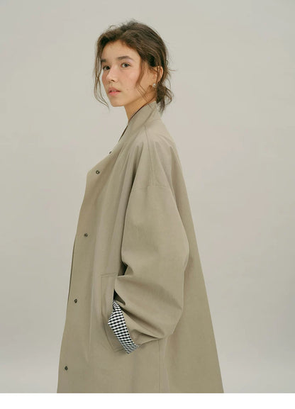 Side view of a Khaki oversized mac coat with stand collar and gingham-lined rolled cuff