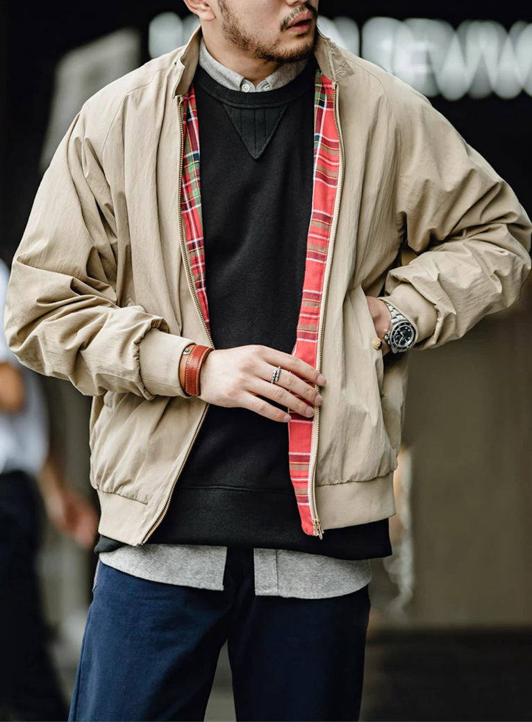 Close-up of model adjusting khaki Harrington jacket with tartan interior