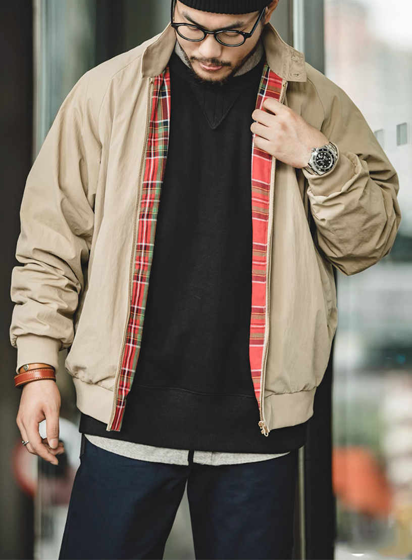 Model wearing khaki Harrington jacket with tartan lining and black sweatshirt