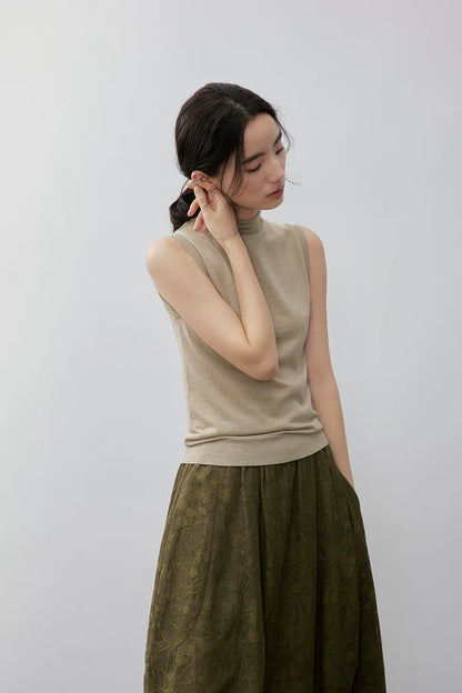 Model in Khaki mock neck sleeveless knit top with hand raised to ear