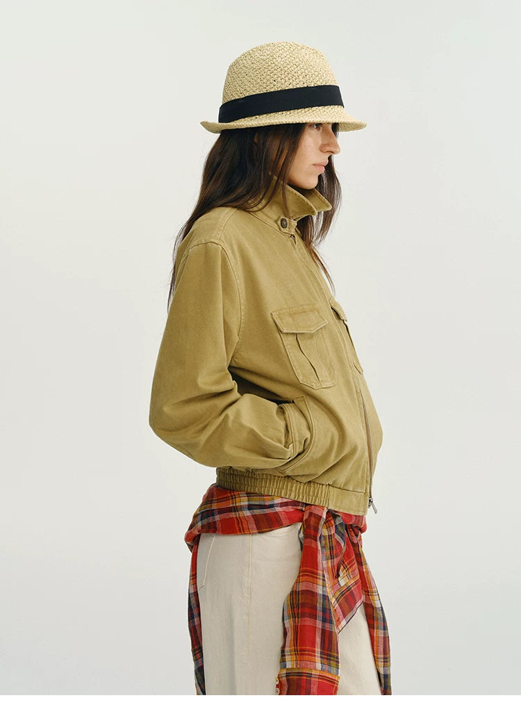 Khaki utility jacket worn with the collar stood up and buttoned, side view