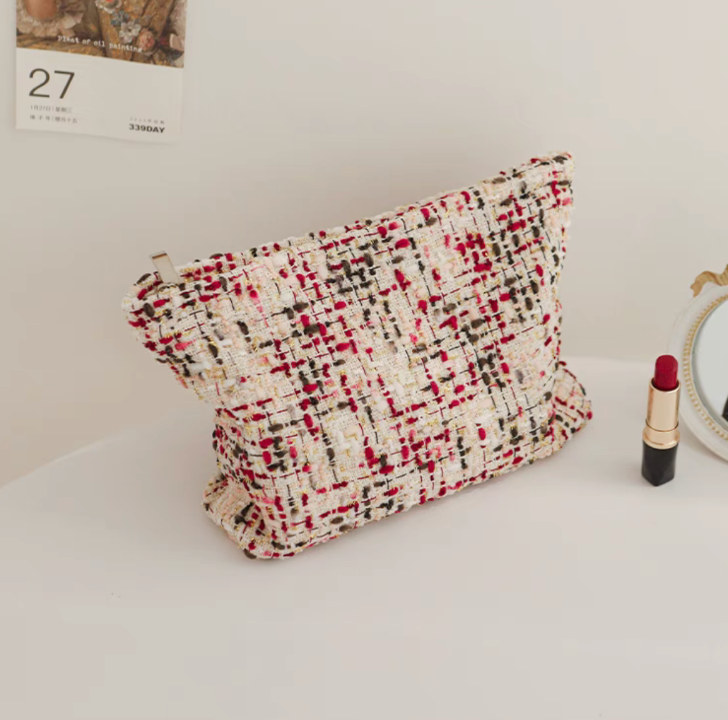 Large Capacity Travel Makeup Bag in purple woven texture placed upright on table with lipstick and mirror beside