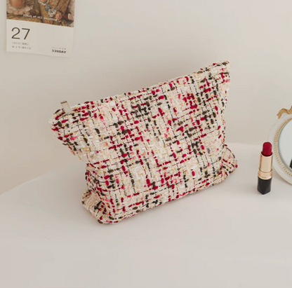 Large Capacity Travel Makeup Bag in purple woven texture placed upright on table with lipstick and mirror beside
