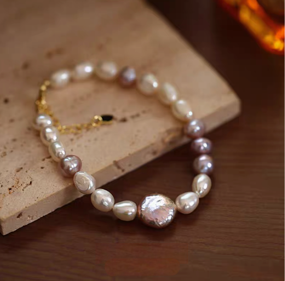 Lavender baroque pearl bracelet in natural color featuring freshwater pearls and adjustable gold clasp on textured surface