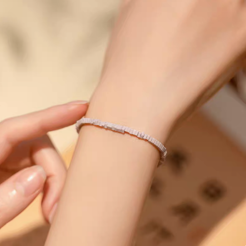 Close-up of lavender lepidolite micro tile bracelet worn on wrist with hand gently touching showing delicate purple bead texture