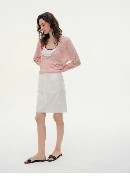 Full-body view of Misty Pink layered V-neck knit paired with white summer skirt