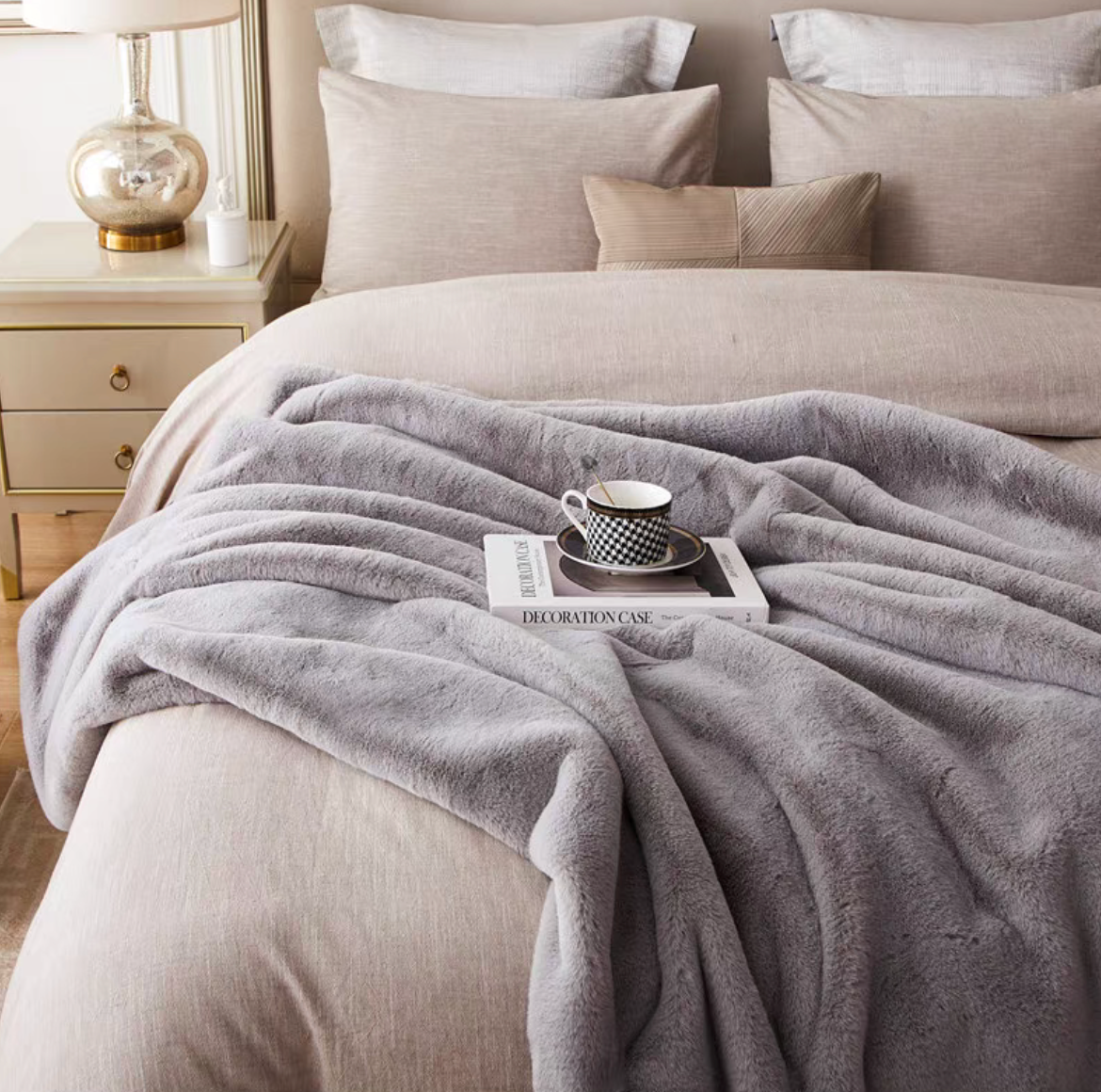 Light gray faux fur throw blanket styled across bed for soft and cozy bedding design