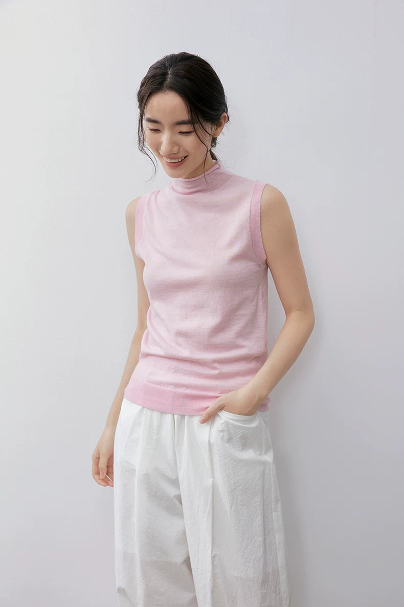 Model looking down in Light Pink sleeveless wool knit top, hand in pocket