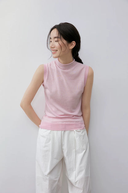 Model glancing sideways in Light Pink sleeveless mock neck wool knit top