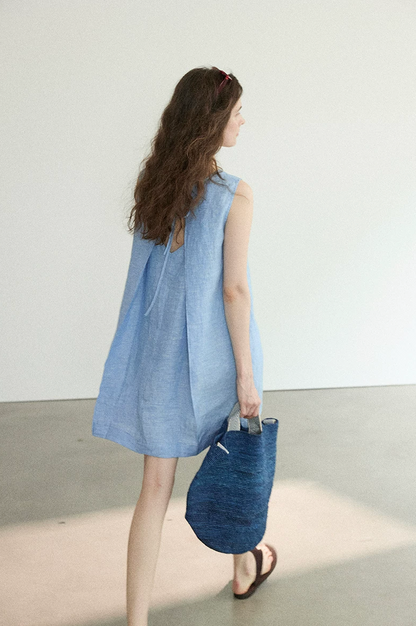 Chambray blue linen A-line dress, back view while walking