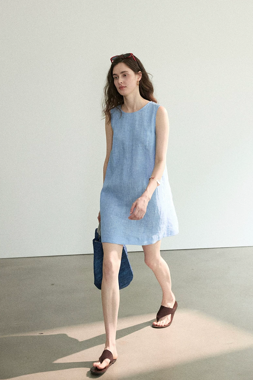 Chambray blue linen A-line dress, front view while walking