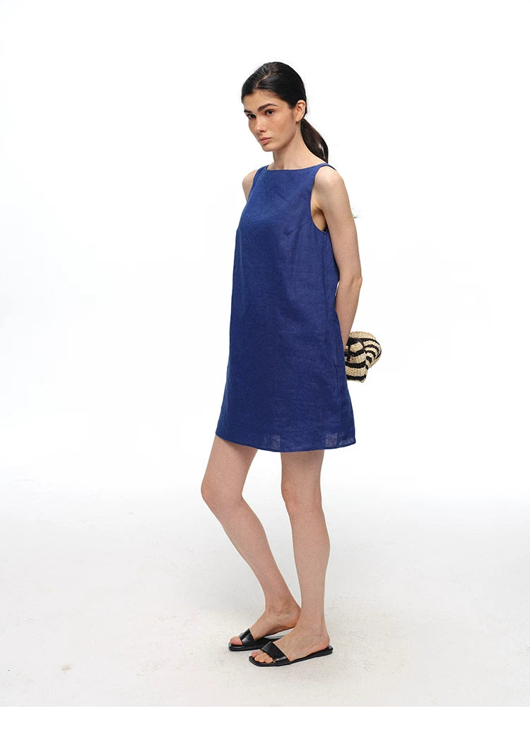 Royal blue linen shift dress styled with woven bag, side view
